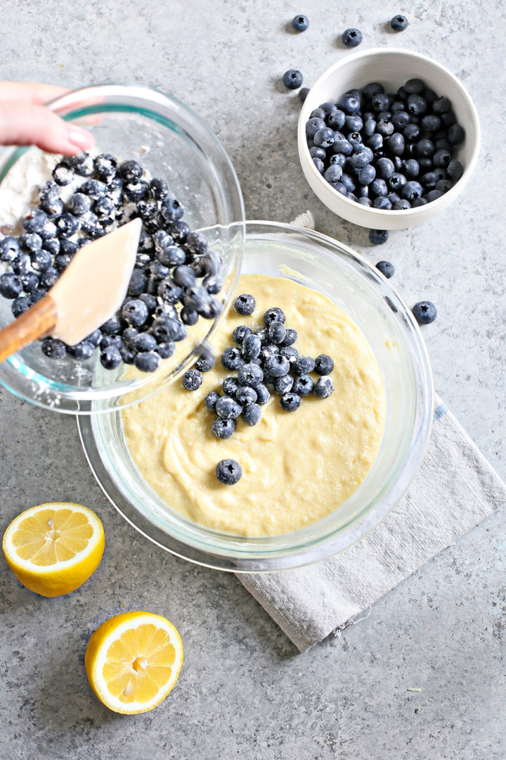 woman adding fresh blueberries into lemon bread batter