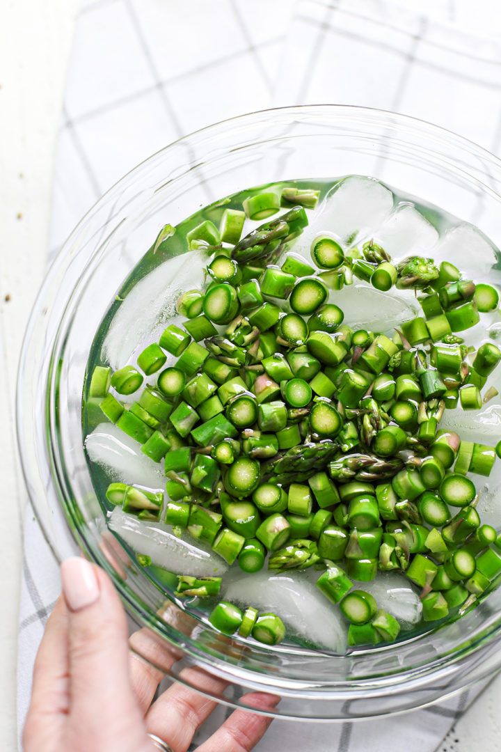 woman blanching fresh asparagus to make asparagus salad with