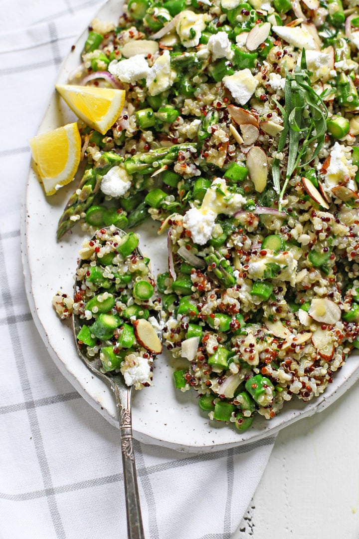 cold asparagus salad with a serving spoon on a white platter