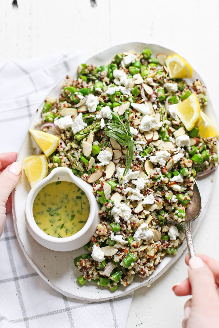 woman stirring asparagus salad on a white platter