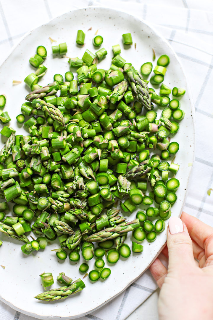 fresh chopped asparagus on a white platter for using in cold asparagus salad