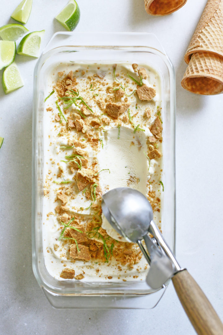 key lime ice cream being scooped out of a glass dish with a metal ice cream scoop