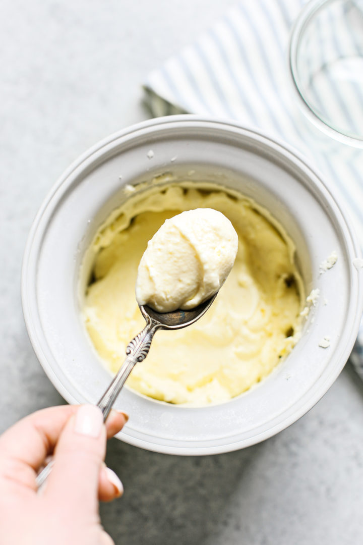 woman holding a spoon of lemon ice cream to sample it after churning