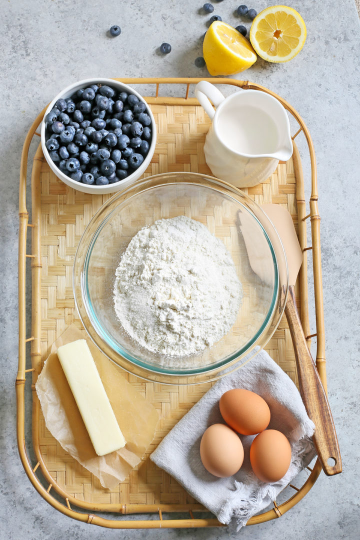 ingredients needed to make lemon blueberry bread arranged on a bamboo tray 