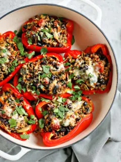 quinoa stuffed peppers in a white baking dish on a grey background