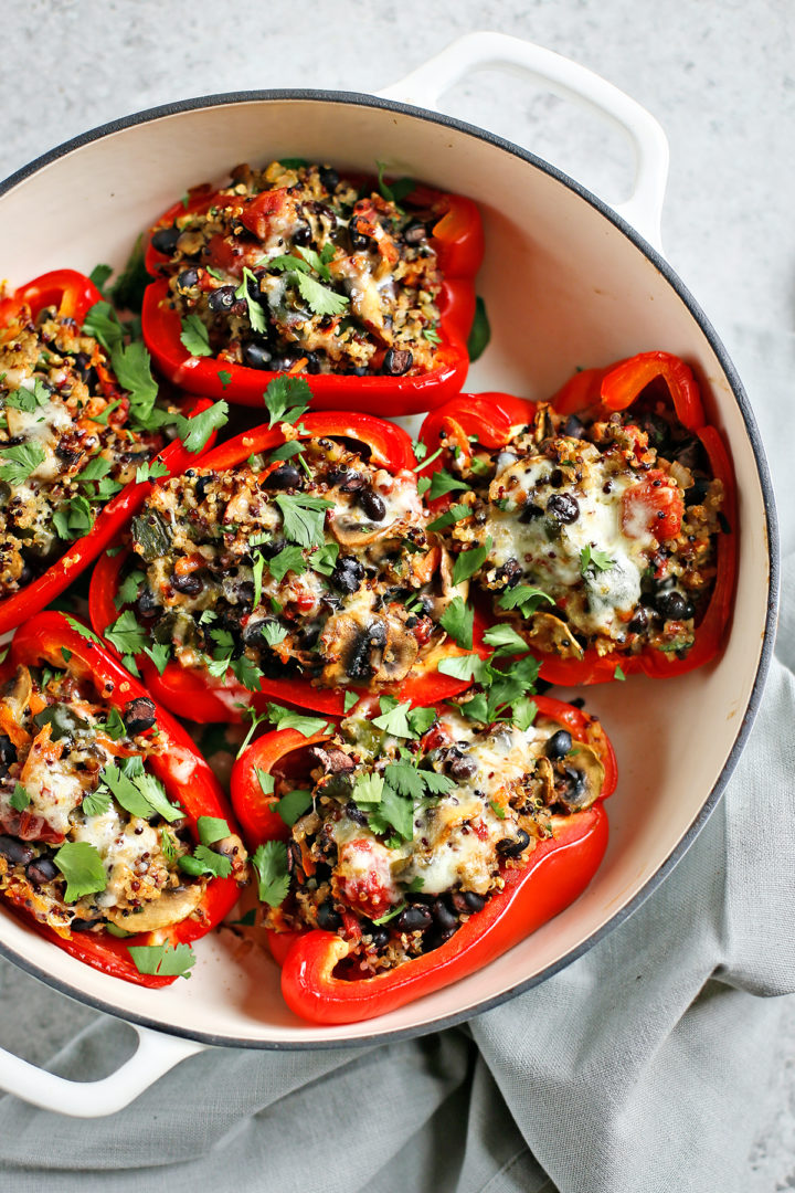 quinoa stuffed peppers in a white cast iron baking dish on a grey background