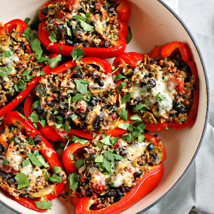 quinoa stuffed peppers in a white baking dish on a grey background