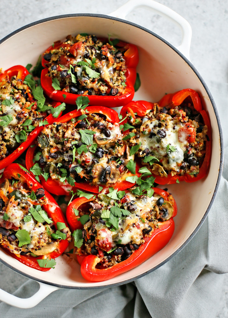 quinoa stuffed peppers in a white baking dish on a grey background