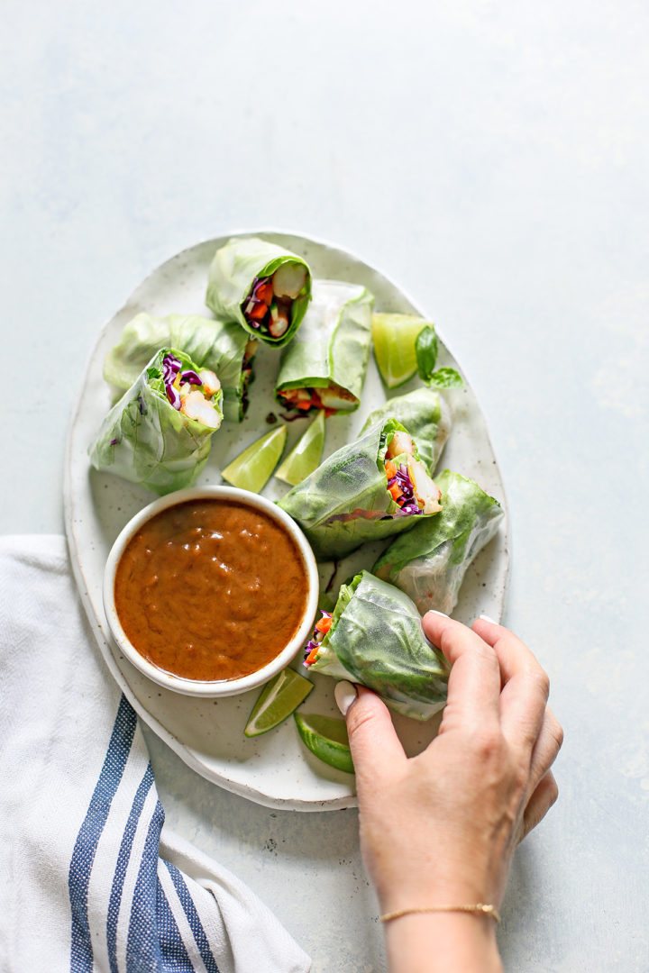 woman picking up a Vietnamese Spring Rolls off a serving platter