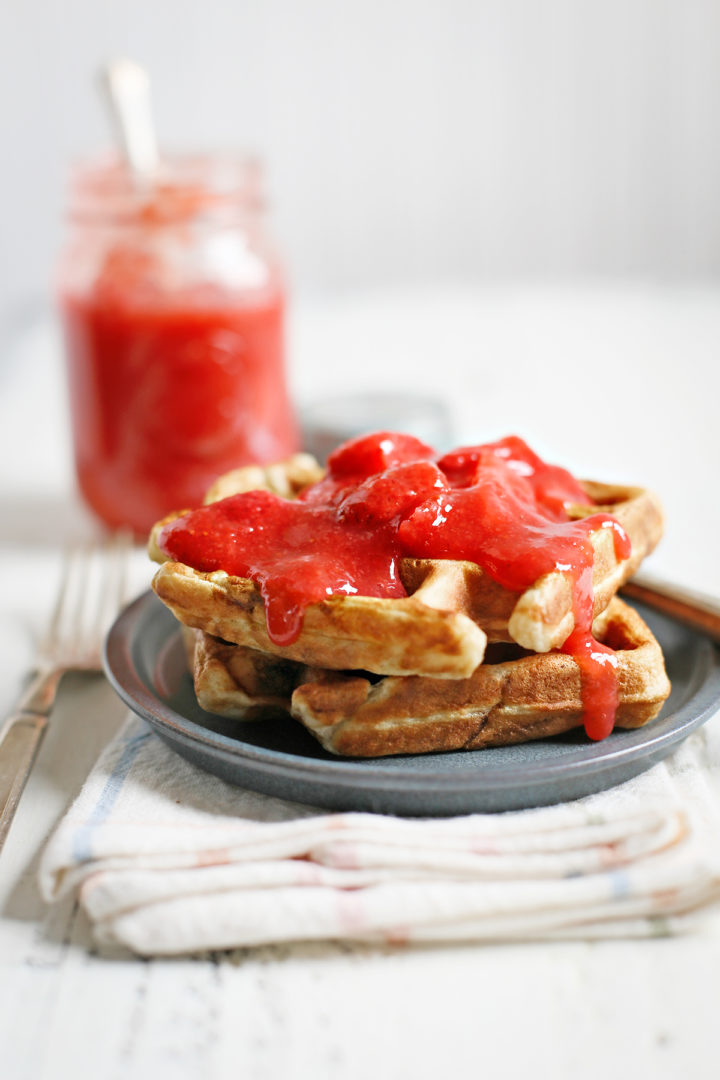 a plate of waffles with fresh strawberry sauce on top