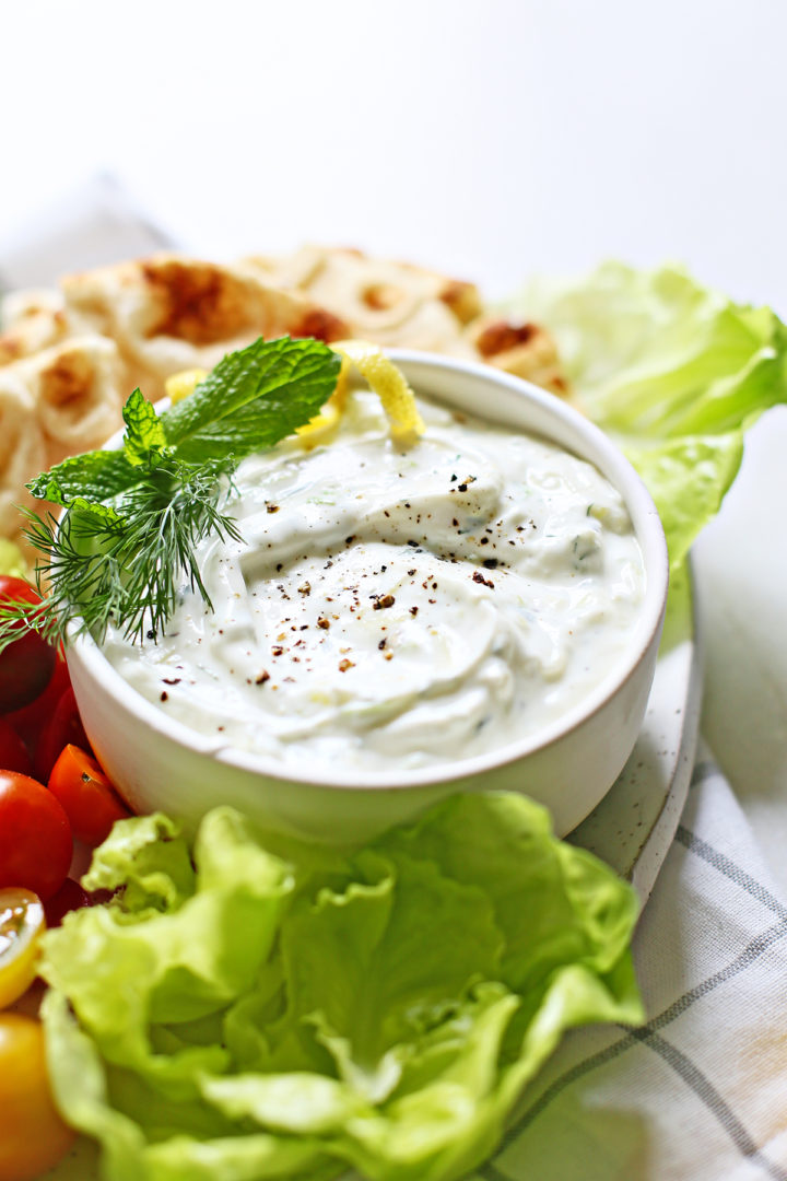 tzatziki sauce recipe in a white bowl with vegetables for dipping