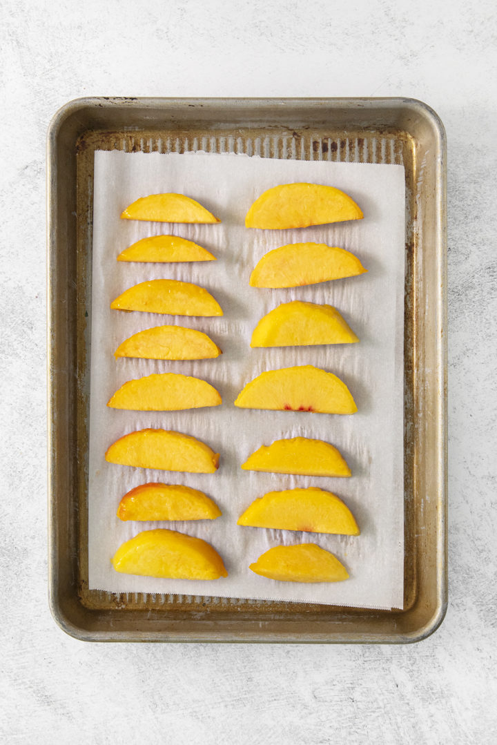 blanched peach slices on a baking sheet lined with parchment paper for freezing