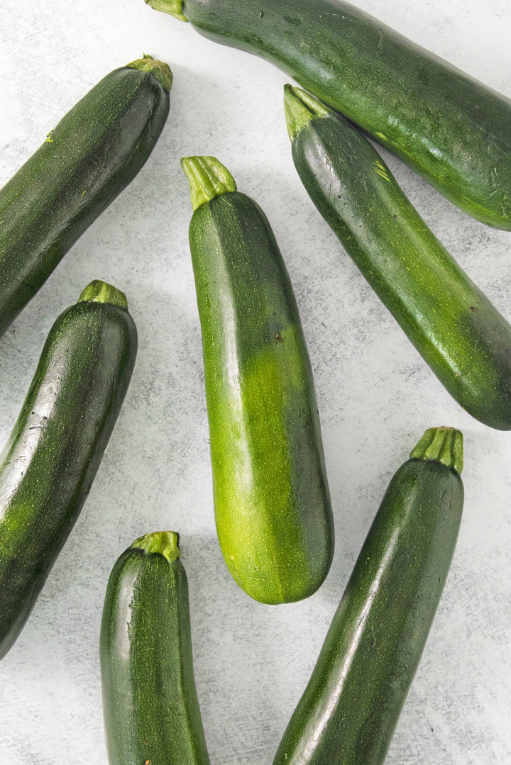 fresh zucchini on a light surface being prepared for freezing