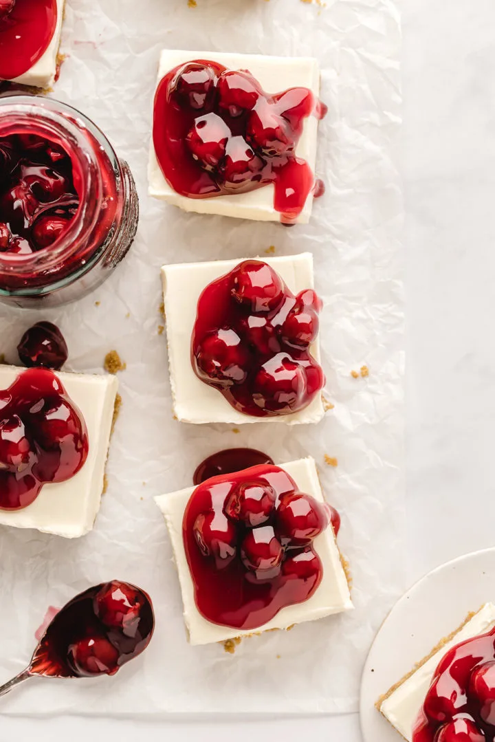 photo of cherry cheesecake bars cut into squares on a piece of parchment paper