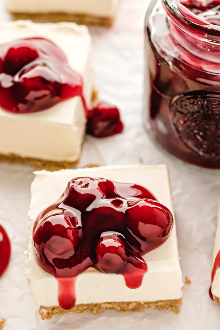 close up of a cherry pie filling topped cheesecake bar