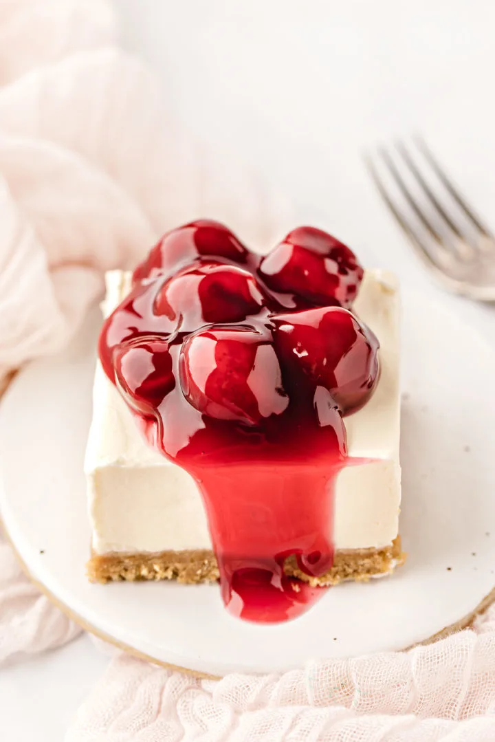 a cherry cheesecake bar on a white plate with a fork