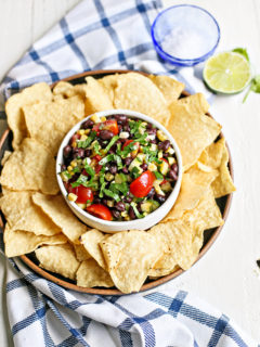 overhead photo of a white bowl of zucchini salsa with tortilla chips surrounding it