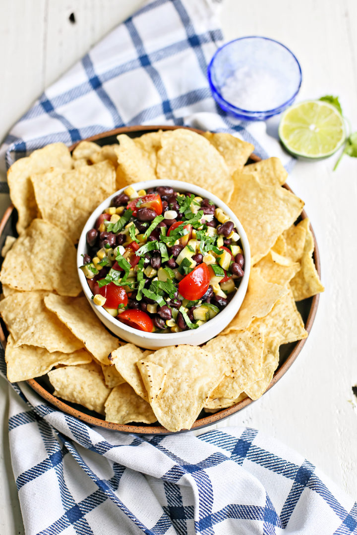 overhead photo of a white bowl of zucchini salsa with tortilla chips surrounding it