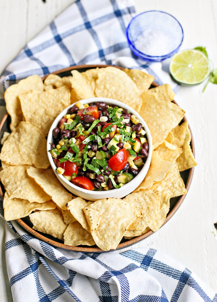 overhead photo of a white bowl of zucchini salsa with tortilla chips surrounding it