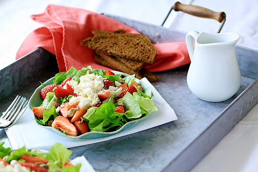 a metal serving tray with plates of strawberry goat cheese salad and sliced bread