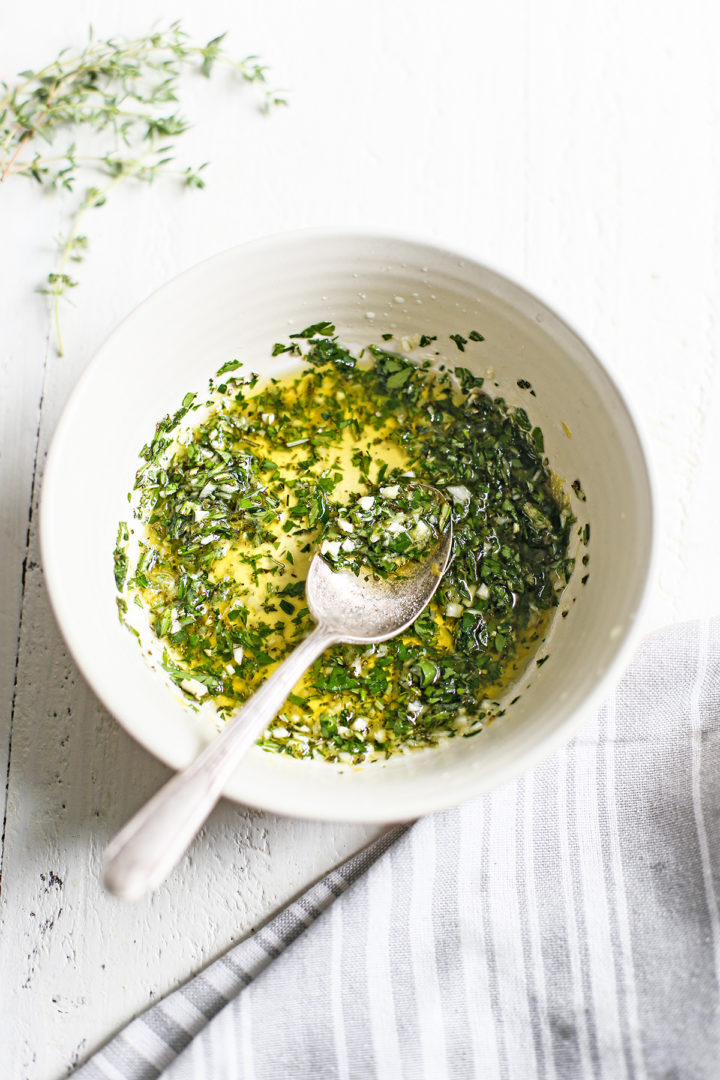 a white bowl of homemade gremolata sauce on a white wooden table