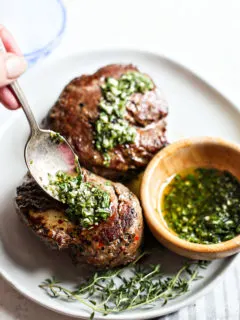 woman spooning gremolata sauce onto seared steaks