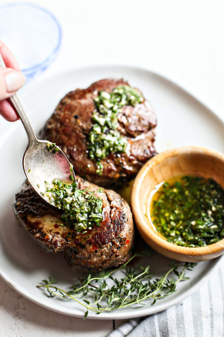 woman  spooning gremolata sauce onto seared steaks