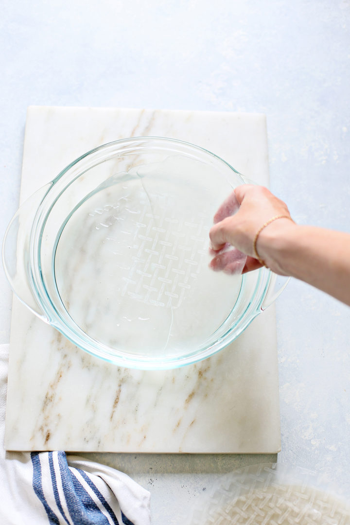 woman showing how to soften rice paper for rolling Vietnamese Spring Rolls