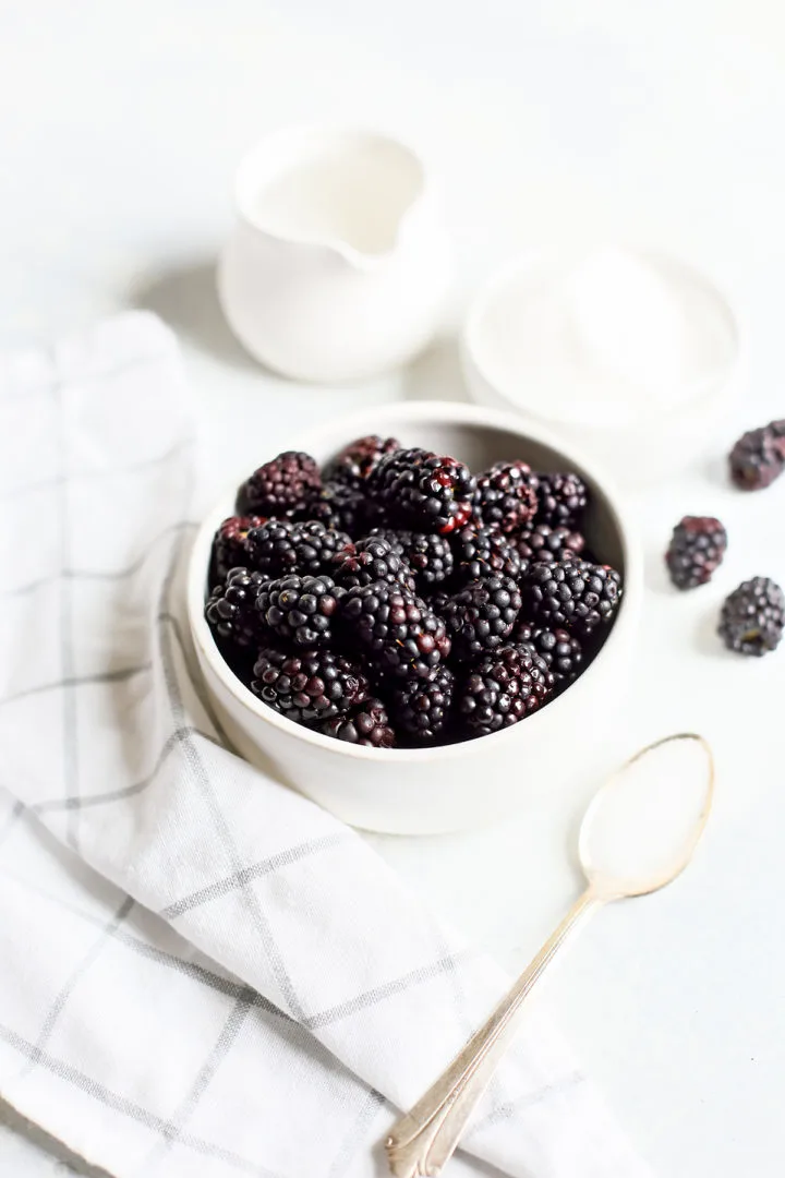 photo of fresh blackberries in a white colander for a tutorial on how to make blackberry simple syrup