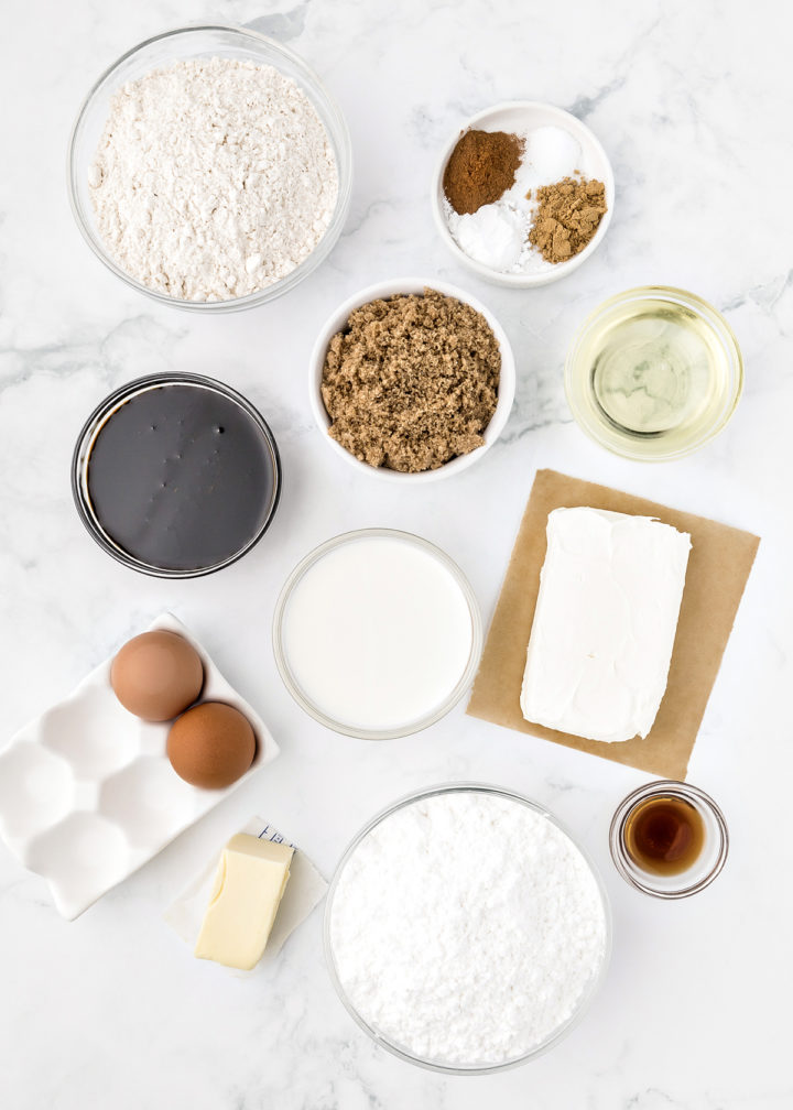 ingredients needed to make gingerbread cupcakes arranged in bowls on a white marble counter