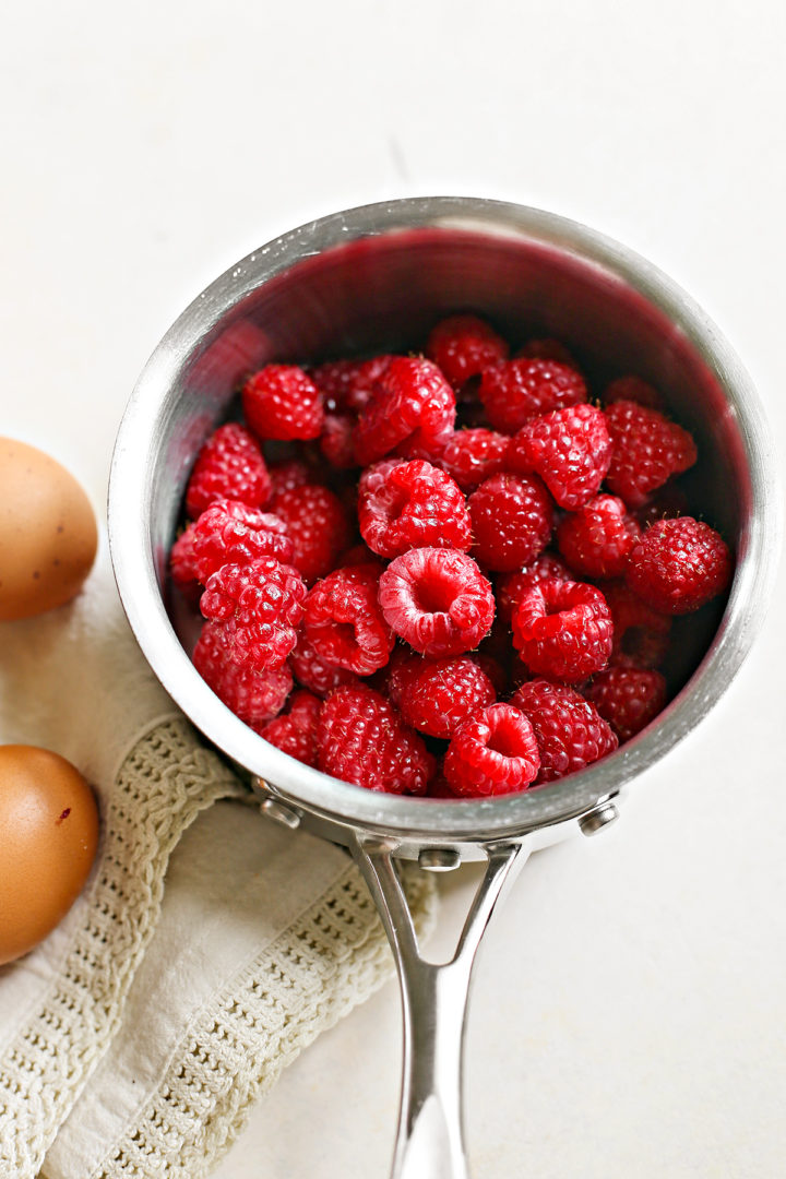 raspberries added to a saucepan with raspberry curd ingredients