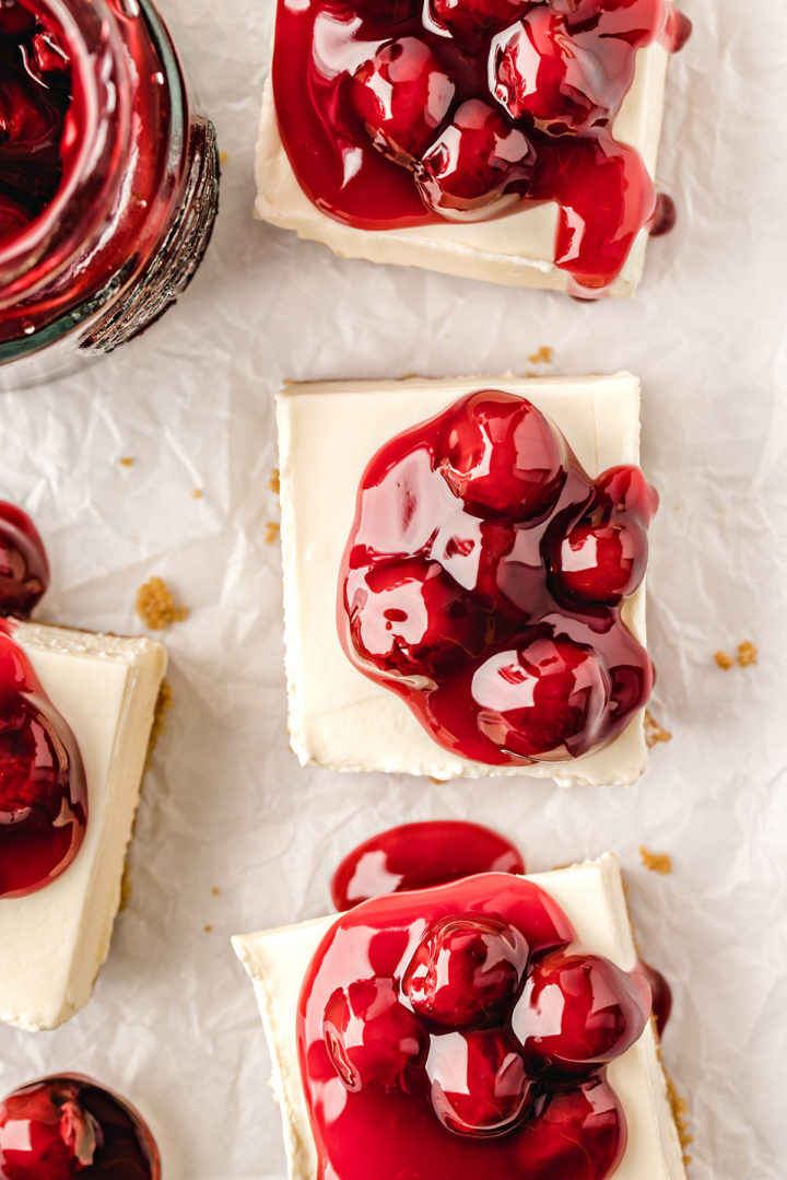 overhead photo of several cherry cheesecake bars on parchment paper