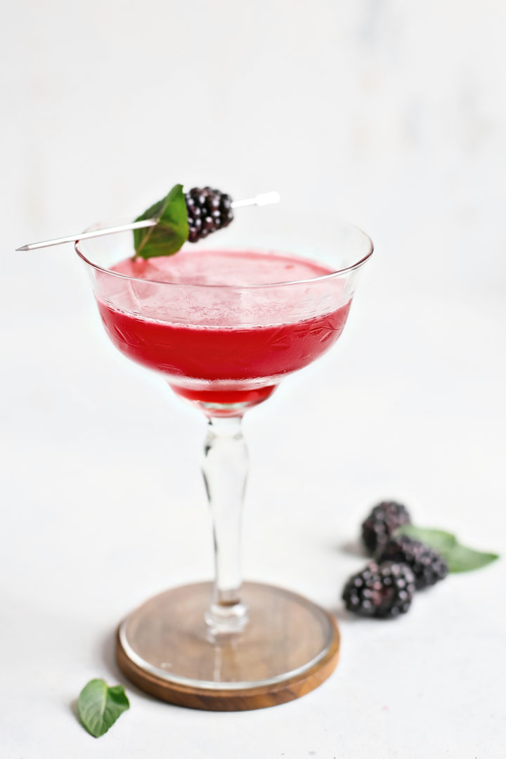blackberry simple syrup in a cocktail glass with fresh blackberries and basil