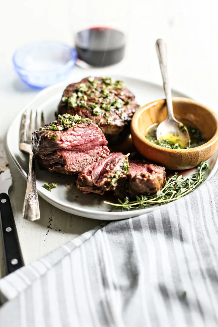 a plate with sliced steak with gremolata in a bowl on the side
