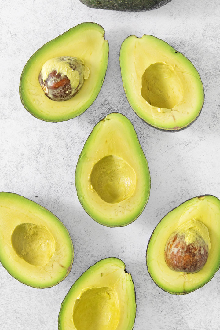 avocados cut in half on a light surface