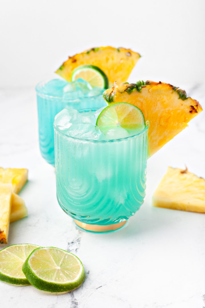 photos of a blue hawaiian (blue curacao cocktail) in glasses garnished with pineapple and lime slices 