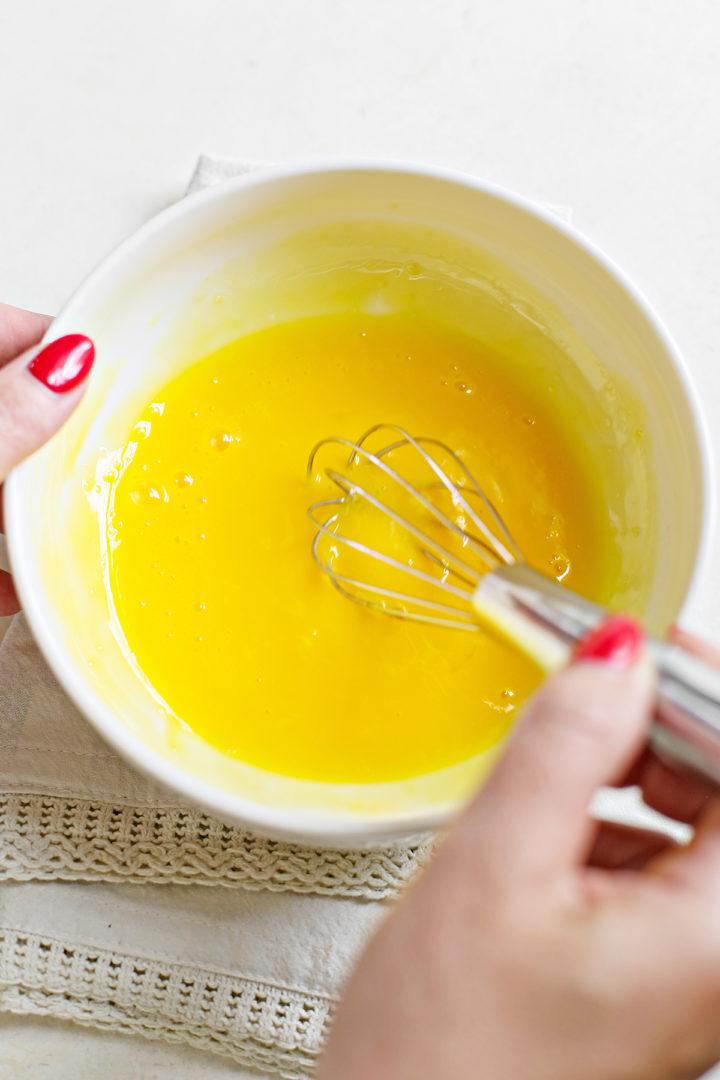 woman whisking egg yolks to make recipe for raspberry curd