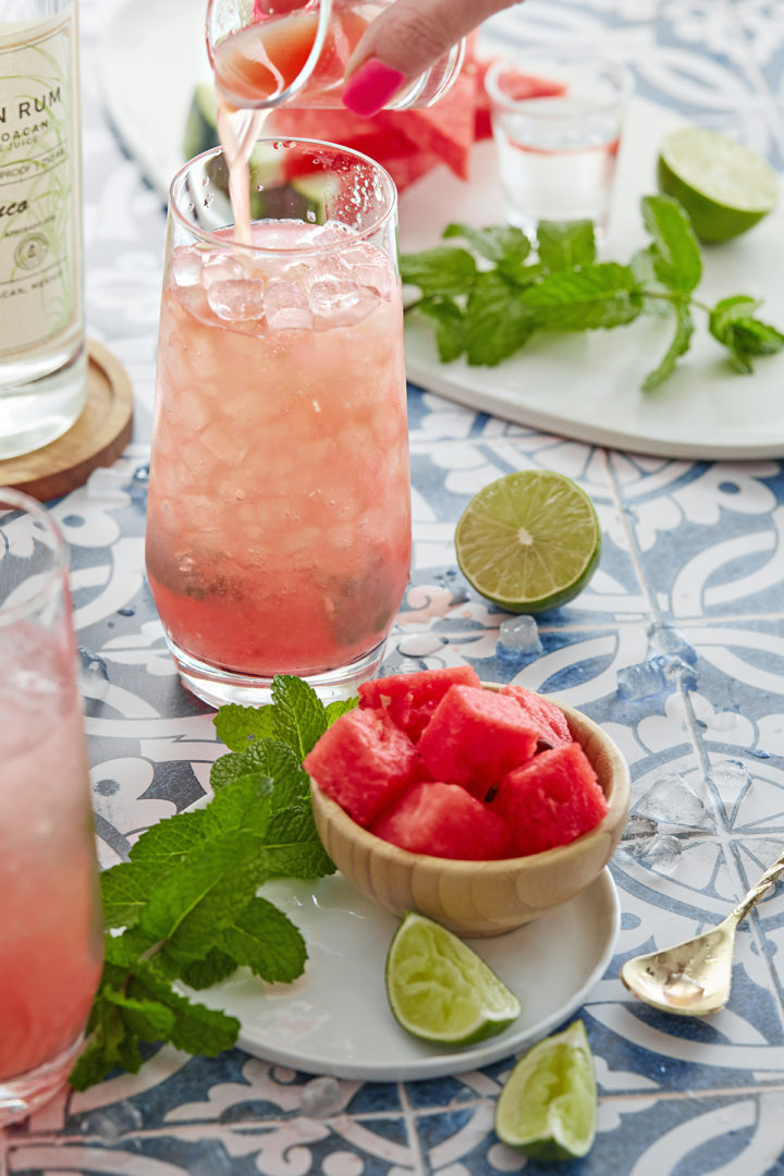 woman adding fresh watermelon juice to a watermelon mint cocktail 
