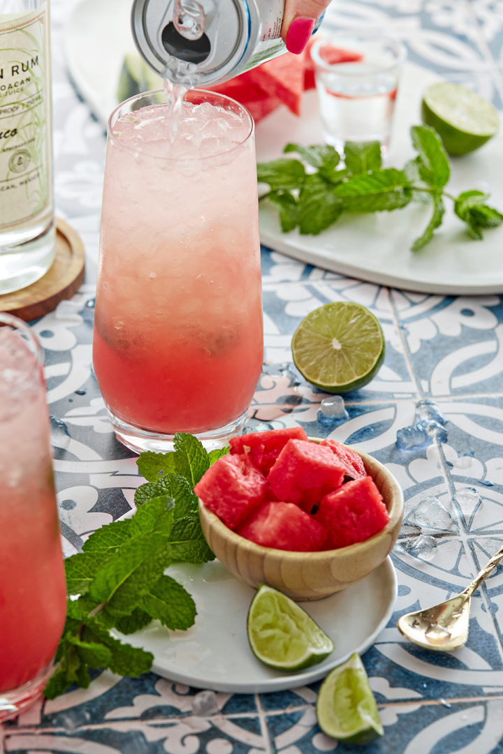 woman adding club soda to a fresh watermelon cocktail
