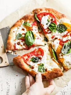 woman picking up a slice of caprese pizza