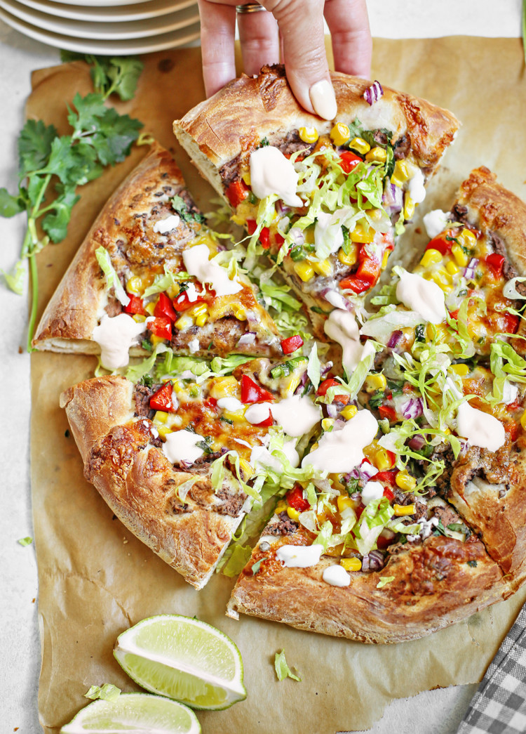 woman picking up a slice of mexican pizza