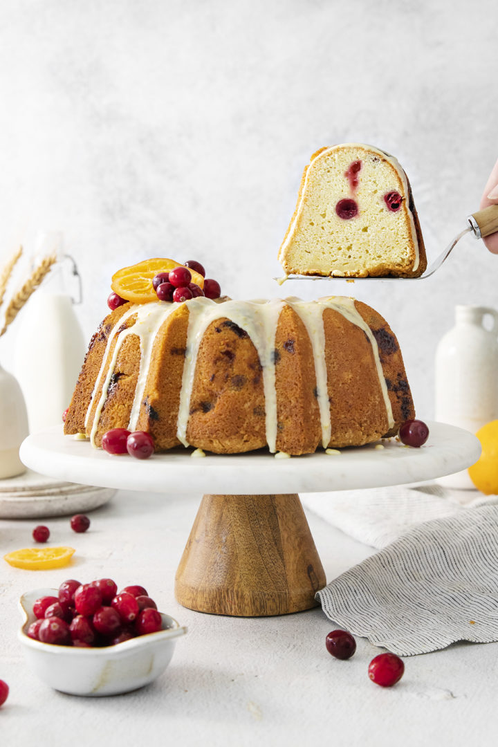 woman serving a slice of cranberry sour cream bundt cake	