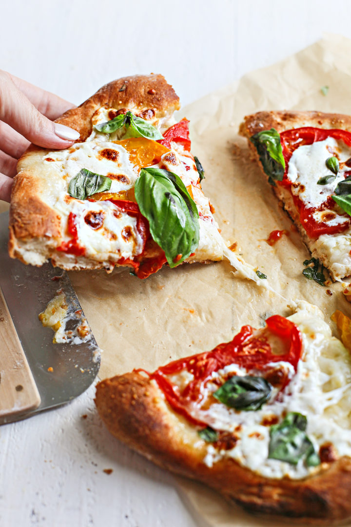 a slice of caprese pizza being served