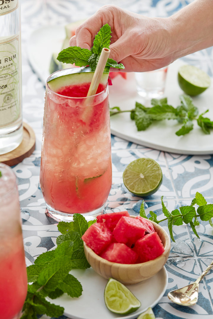 woman garnishing a fresh watermelon cocktail with fresh mint