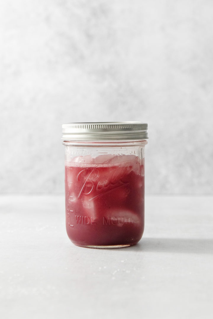 photo of ingredients for a blood orange cocktail combined in a mason jar with ice