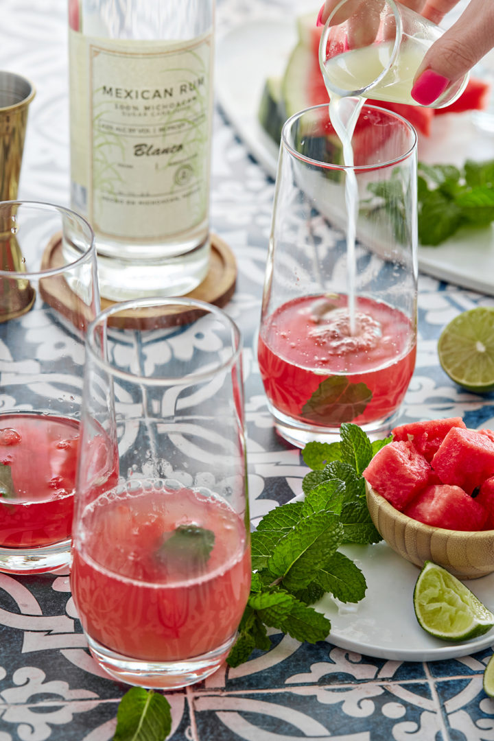 woman preparing a watermelon rum cocktail - adding fresh lime juice to a glass