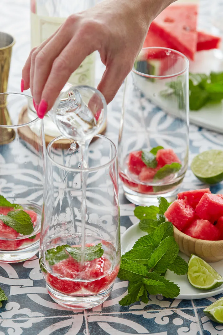 woman adding simple syrup to fresh watermelon and mint cocktail recipe