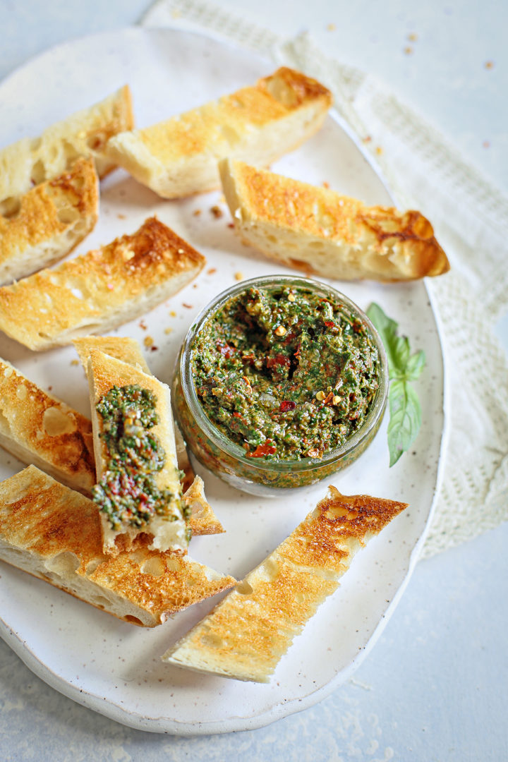 a sun dried tomato pesto crostini appetizer on a white serving plate