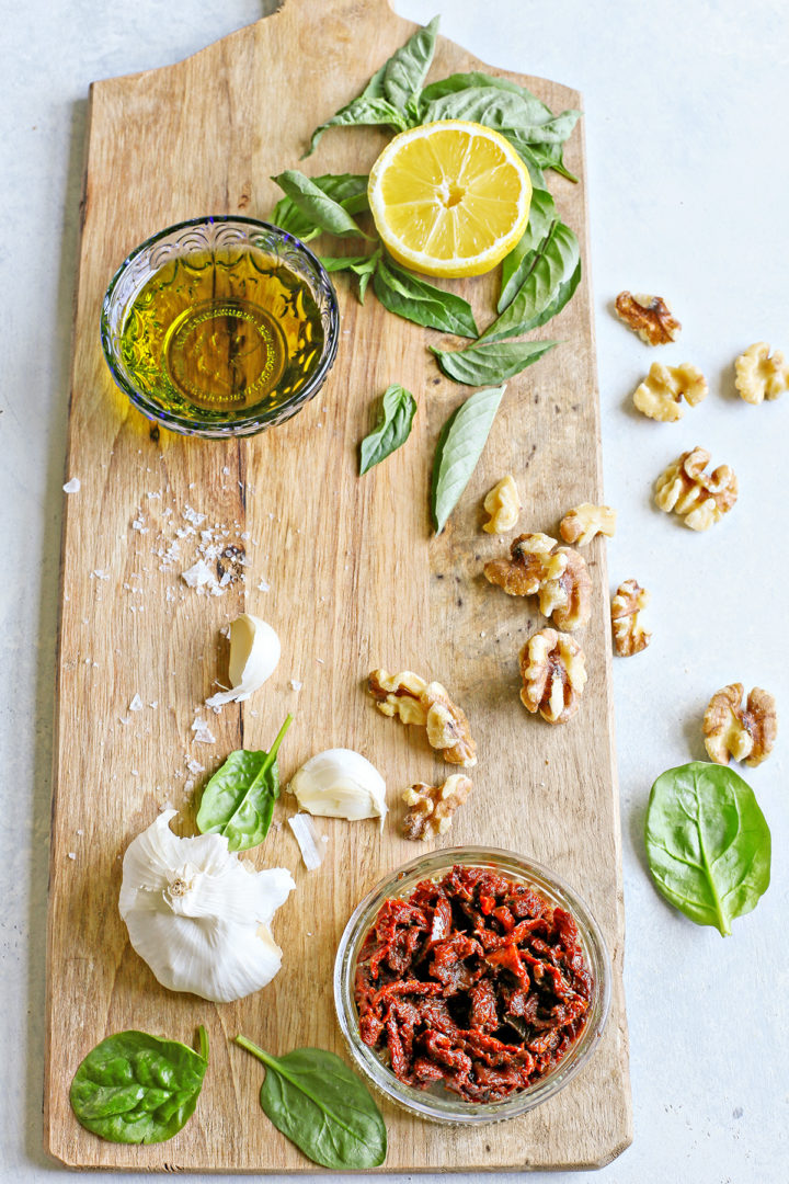 ingredients in sun dried tomato pesto on a wooden cutting board
