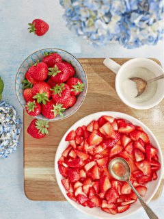 overhead photo of a bowl of macerated strawberries on a cutting board